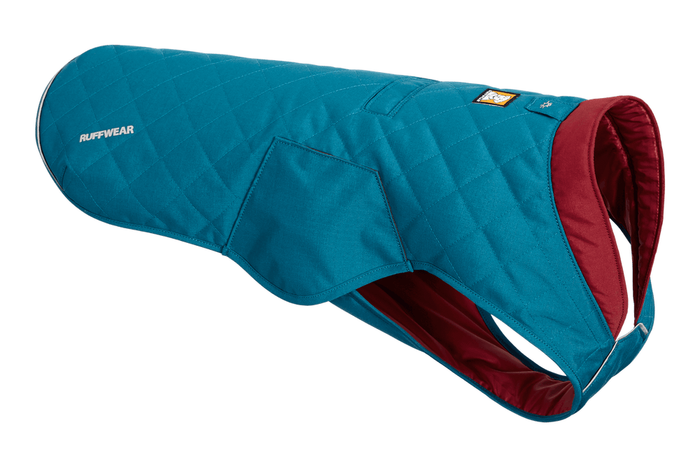 Teal-farbener gesteppten Hundemantel von Ruffwear mit karierter Textur und roter Innenfarbe für Wärme und Komfort.