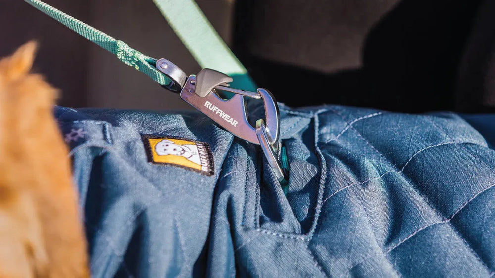 Blauer gesteppter Hundemantel von Stumptown™ mit Clip zur Befestigung an Geschirr oder Leine und Ruff-Logo.