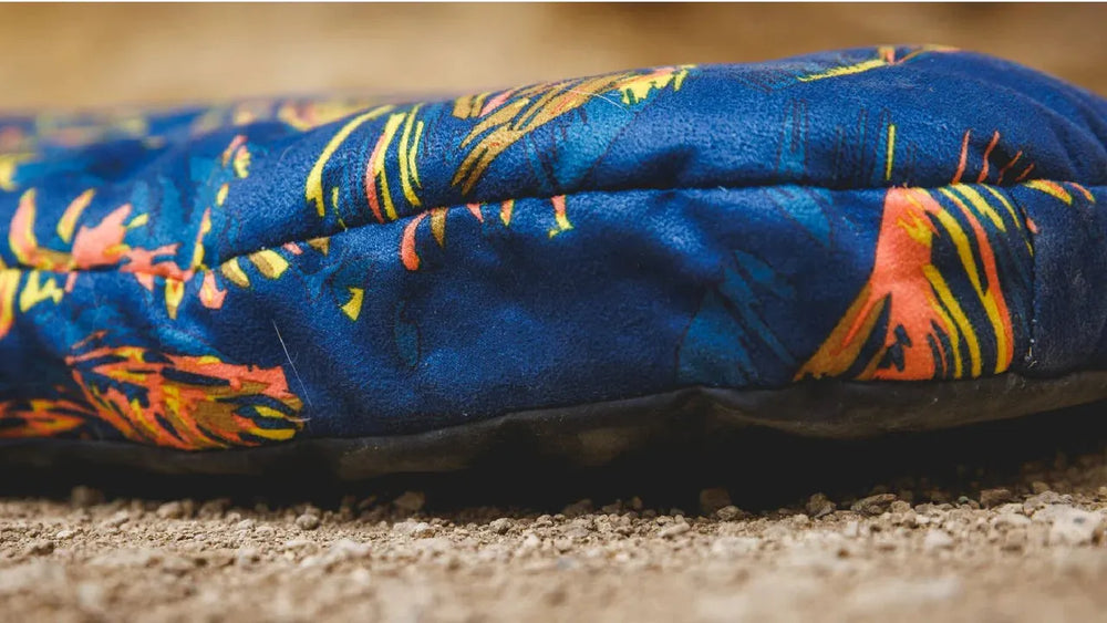 Faltbares Hundebett in Blau mit bunten Blumenmustern, ideal für gemütliche Ruheplätze im Innen- und Außenbereich.
