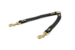 Schwarzer Lederhalsbandverbinder für zwei Hunde mit goldfarbenen Haltestellen und Karabinerhaken.