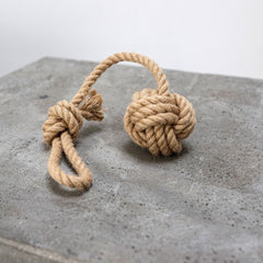 Knoten aus Jute- und Hanfseil auf grauer Betonoberfläche, dekorativ und natürlich.
