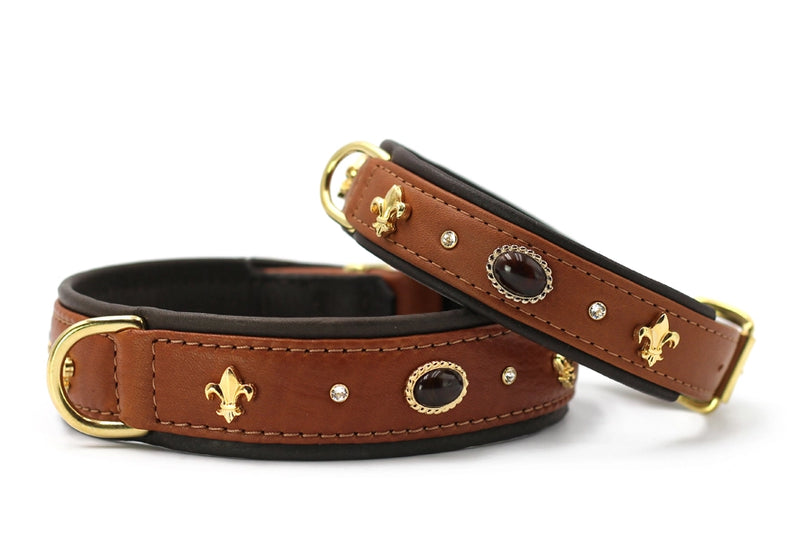 Braune Lederhundehalsbänder mit goldenen Beschlägen und ovalem Kristall, dekoriert mit stilisierten Lilienmotiven.