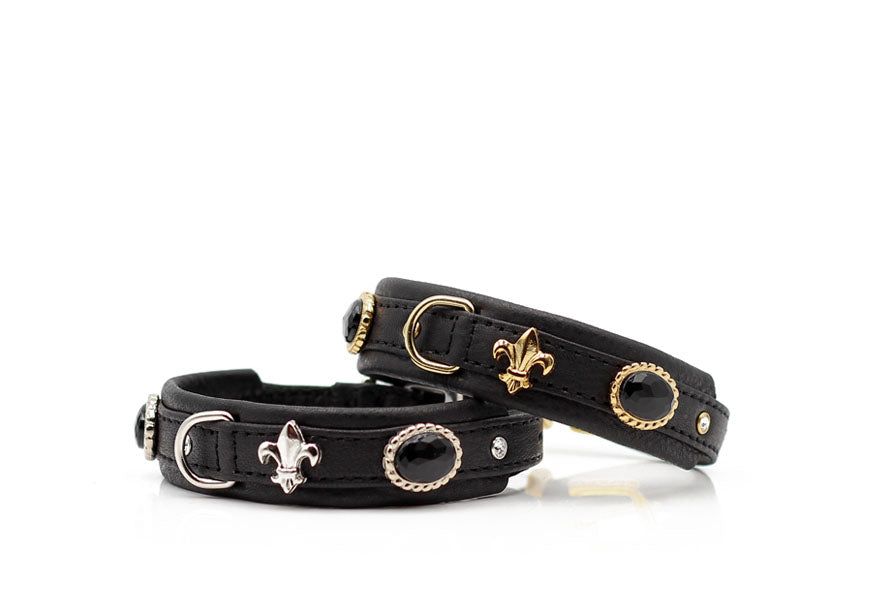 Schwarze Lederarmbänder mit Fleur-de-Lis-Symbolen und schwarzem Stein als dekorativem Element.