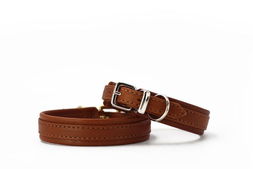Zwei elegante braune Lederarmbänder, eines mit silberner Schnalle, sorgfältig genäht für stilvolle Accessoires.