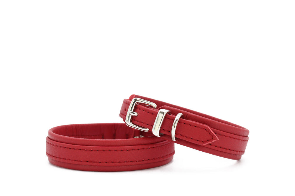 Zwei rote Lederarmbänder: eines mit verstellbarer Schnalle, das andere ohne Verschluss, beide mit dekorativer Naht.