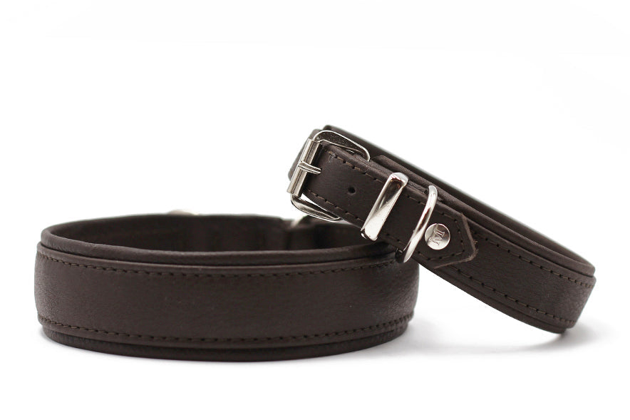 Zwei braune Lederarmbänder: ein breiteres, flaches und ein schmaleres mit Schnalle zur Justierung. Glatte Oberfläche.