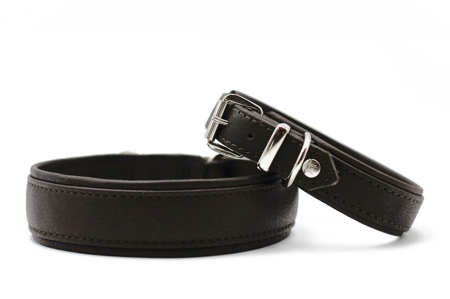 Zwei braune Lederhalsbänder: eines schmal mit Schnalle, das andere breiter und schlicht. Perfekt für stilvolle Haustiere.