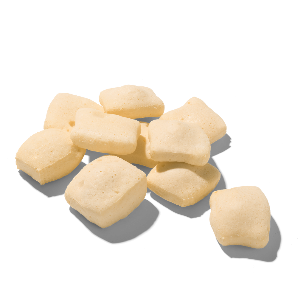 "FRED Käsepops Rind: Kleine, helle, quaderförmige Snacks mit poröser Textur auf einer Fläche verteilt."