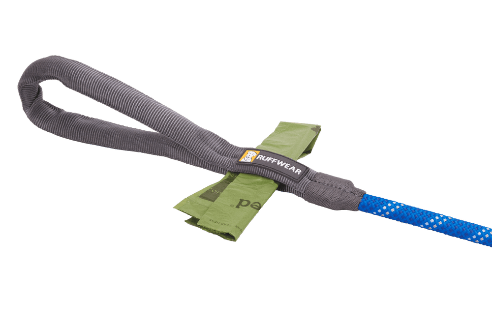 Ruffwear Knot-a-Leash™: Graue gepolsterte Hundeleine mit blauem, geflochtenem Ende und Hundekotbeuteln im Hintergrund.