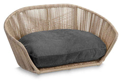 Modernes ovales Hundebett TUDOR aus hellem Rattan mit gepolstertem grauem Kissen im stilvollen VOGUE-Design.
