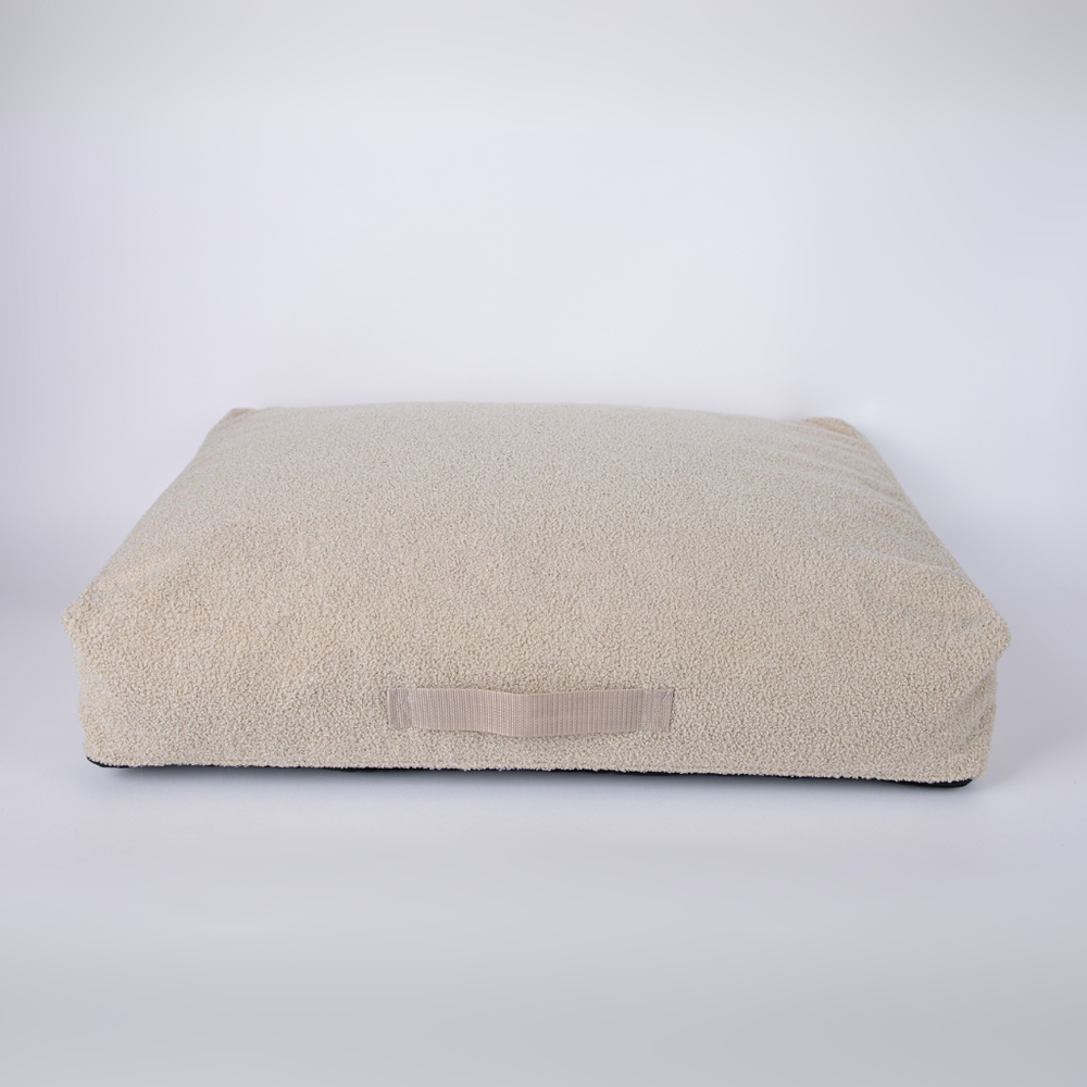 Beiges Hundebett Teddy mit flauschiger Oberfläche und Griffschlaufe, ideal für Komfort und Entspannung.