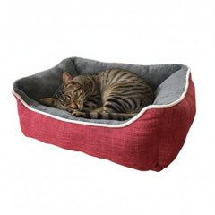Gemütliches rotes Katzenbett "ARNO" mit grauem Innenfutter, in dem eine getigerte Katze entspannt schläft.