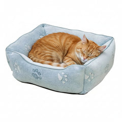 "Rechteckiges Kuschelbett 'PAW' für Katzen in Blau mit Pfotenabdrücken und schlafender oranger Katze."