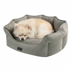 "Bequemes ovales Hundebett 'ANDA' in grau mit schlafendem Pomeranian darin, hohe Umrandung und weiche Polsterung."