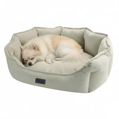 Hund auf grauem ovalem Komfortbett "CORDO" mit erhöhten Rändern, ideal für gemütliche Ruhepausen.