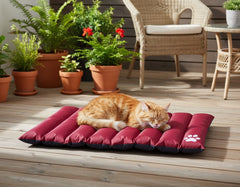 "Orange Katze schläft auf rot-grauer Wendematte 'Anon' auf Holzfußboden, umgeben von blühenden Pflanzen."