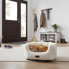 "Gemütliches ovales Katzenbett 'KAMBA' mit schlafender orangefarbener Katze in einem hellen Raum."