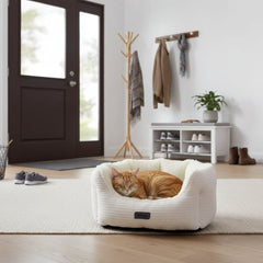 "Gemütliches ovales Katzenbett 'KAMBA' mit schlafender orangefarbener Katze in einem hellen Raum."