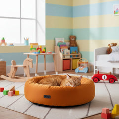 Gemütlicher Katzenkorb in buntem Kinderzimmer, katze liegt entspannt, im Hintergrund Spielzeuge und Holzspielzeugpferd.