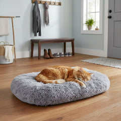 Gemütliche graue Komfortmatte Kabarik mit schlafender orangefarbener Katze in hellem Raum mit Holzfußboden.