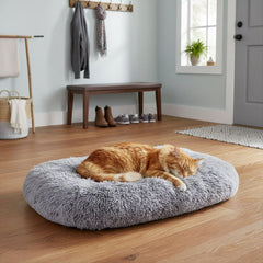 Gemütliche graue Komfortmatte Kabarik mit schlafender orangefarbener Katze in hellem Raum mit Holzfußboden.