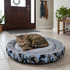 Katze entspannt in rundem, gestreiftem Donut-Bett ELIO im Flur neben Holztür. Komfort für Ihren vierbeinigen Freund.
