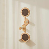 Moderner Wandhaken aus Holz in geschwungener Form mit drei runden Komponenten und hölzernen Stäben zur stabilen Befestigung.