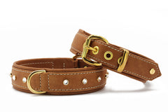Braune Kunstleder-Hundehalsbänder mit goldfarbenen Beschlägen und Schmucksteinen, eines mit D-Ringen für die Leine.