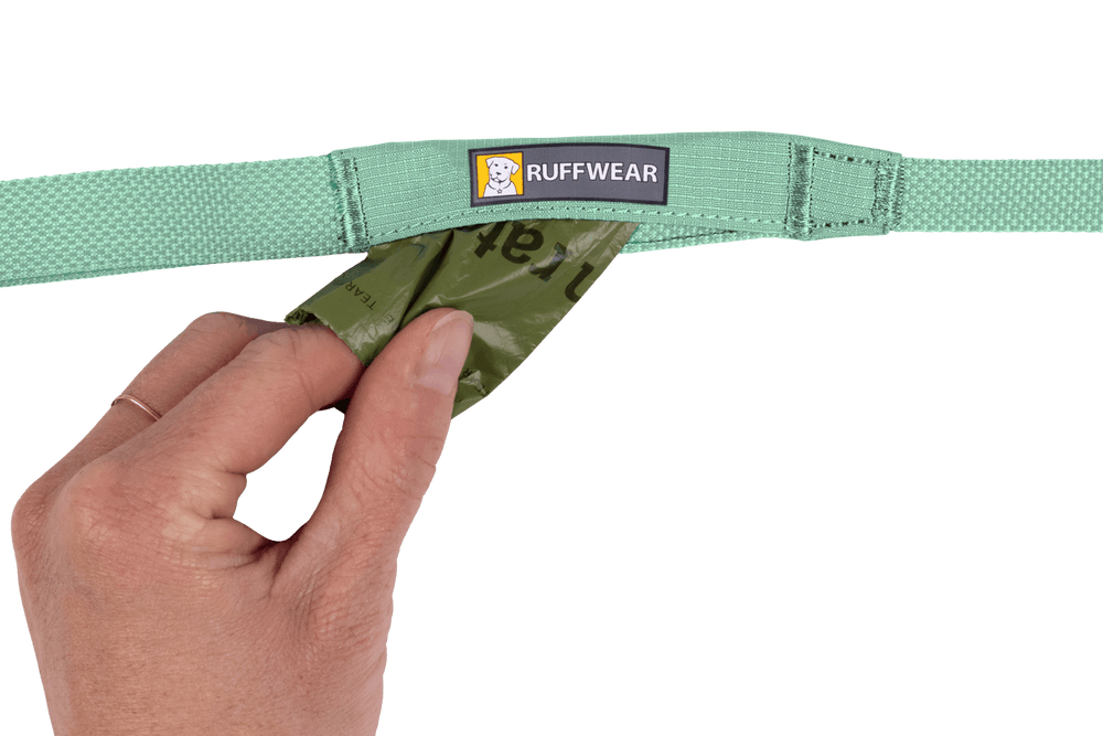 "Ruffwear Hi Light™ Hundeleine in Grün mit integrierter Tasche und Beutel für Hundekot, gehalten von einer Hand."