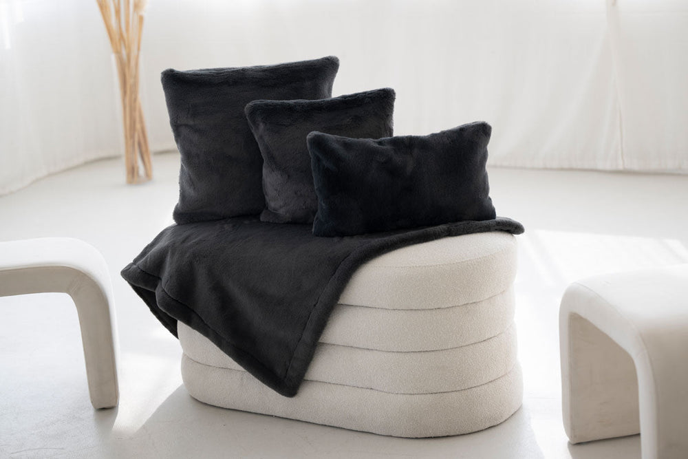 "Moderne oval gepolsterte Sitzgelegenheit mit dunklen Kissen auf hellem Stoff, ideal für stilvolle Wohnräume."