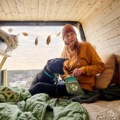 Gemütlicher Van mit Mensch und Hund, ideal für Ausflüge mit Snackbeutel Treat Pocket ECO, im Hintergrund Wald und See.