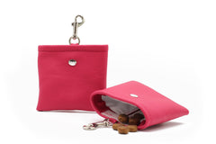 Pinke Leder-Geldbörse mit Druckknopfverschluss und Schlüsselanhänger, halb geöffnet und mit Leckerlis gefüllt.