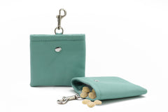 Mintgrünes Leder-Portemonnaie mit Clipverschluss, offen mit herausfallenden kleinen runden Leckerlis.