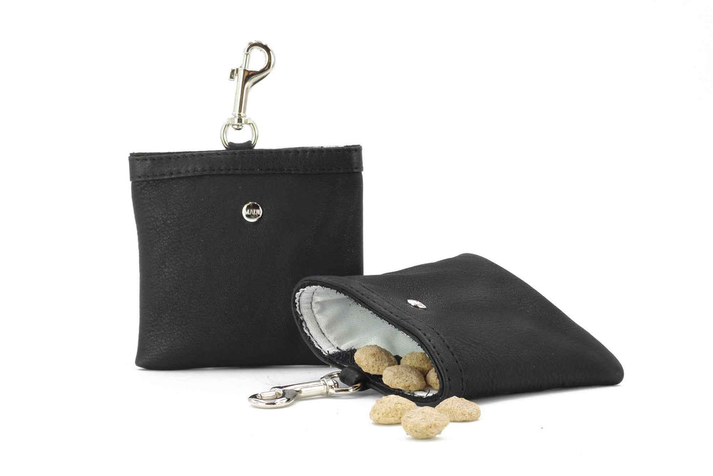 "Schwarzes, ledernes Portemonnaie mit Karabiner, gefüllt mit runden Snacks, auf einem Tisch liegend."