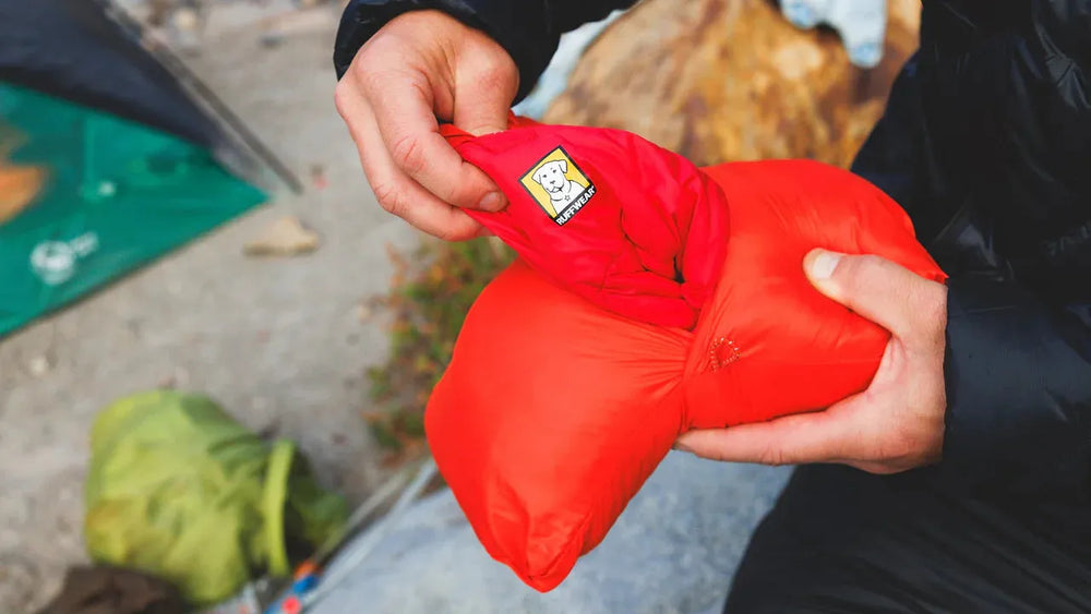 "Person hält roten Palisades™ Schlafponcho, der leicht und kompakt gefaltet ist, ideal für Outdoor-Aktivitäten."