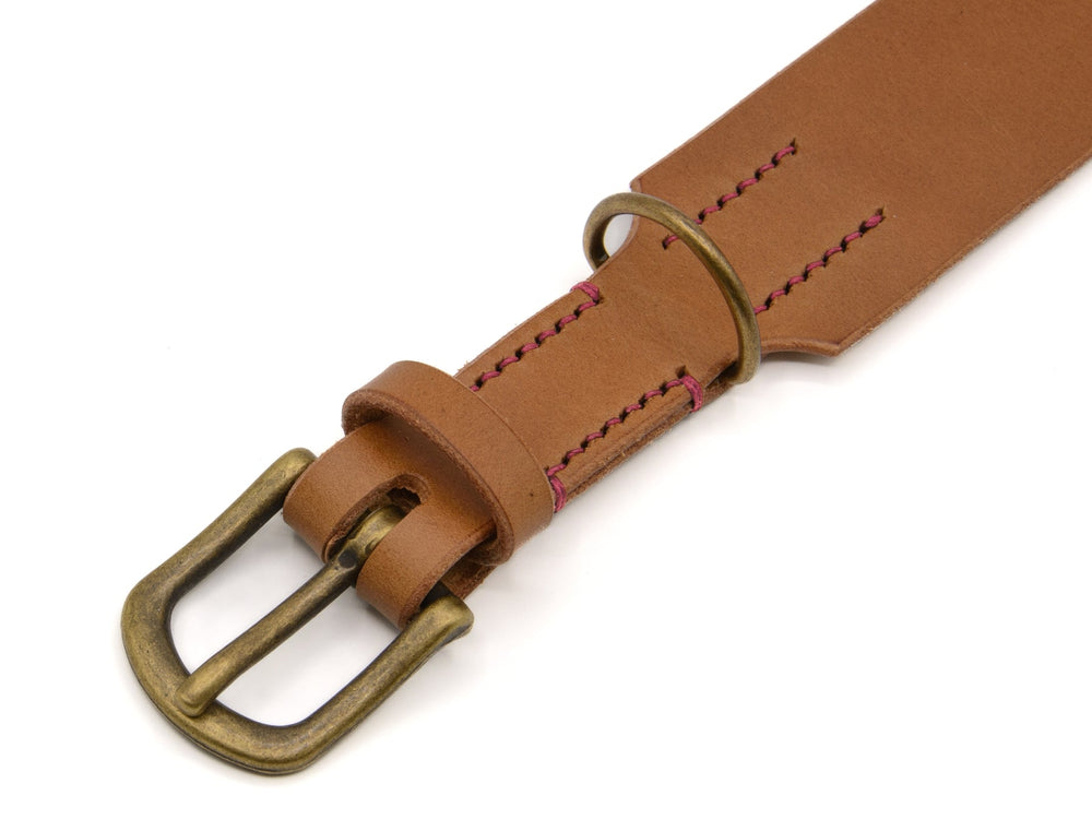 Brauner Ledergürtel mit antiker Metallschnalle und roter Naht, geknickt am Ende mit Gürtelring.