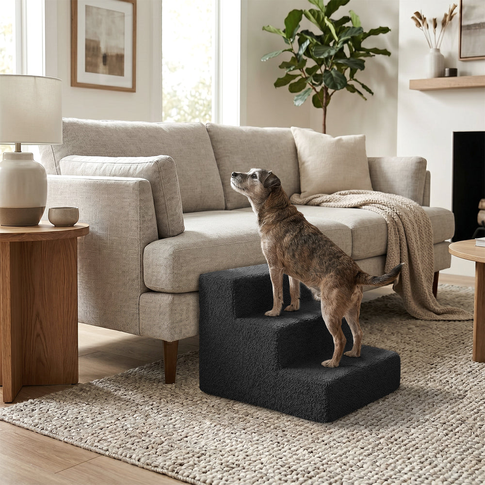 Hund auf grauer Nubosteps Bouclé-Treppe vor beigem Sofa in einem stilvollen Wohnambiente.