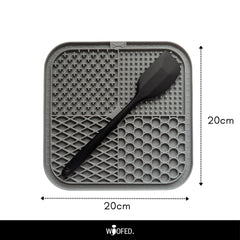 Schleckmatte aus Silikon, quadratisch (20 cm), mit strukturierten Bereichen und schwarzem Spachtel für abwechslungsreiche Snacks.