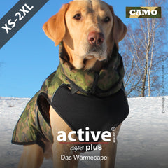 Hund im camouflage Wärmecape auf schneebedecktem Boden, umgeben von Bäumen. Ideal für Outdoor-Aktivitäten.