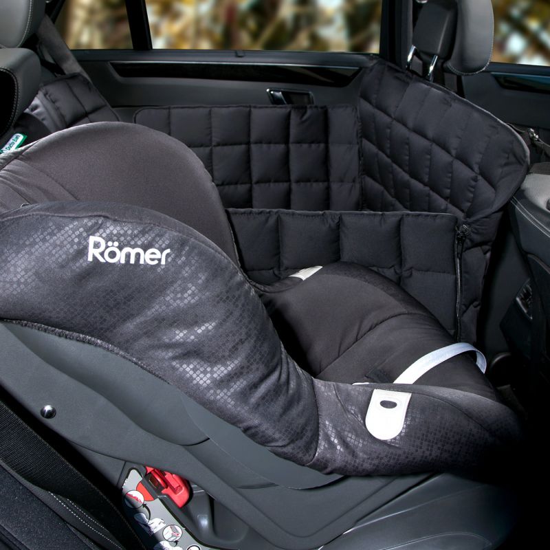 Autokindersitz von Römer in schwarz mit strukturiertem Muster vor Schutzbarriere, ideal für Sicherheit und Komfort.