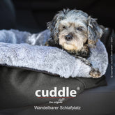 Kuscheliges Hundebett von cuddle.up® mit grauem Plüschrand und schwarzer Basis, kleiner Hund liegt entspannt drauf.
