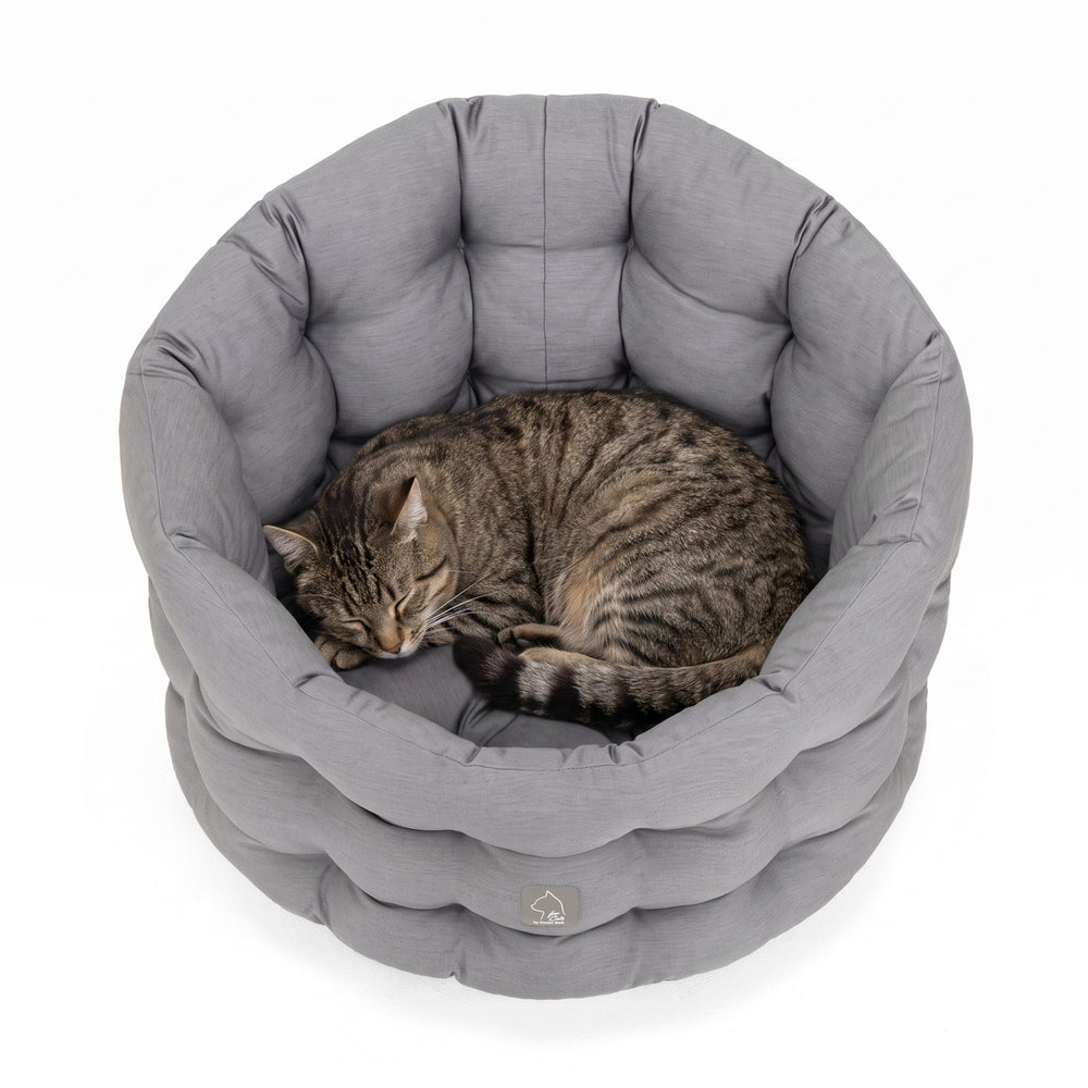 Graues, rundes Katzenbett mit weicher Polsterung und einer schlafenden Katze in der Mitte für optimalen Komfort.