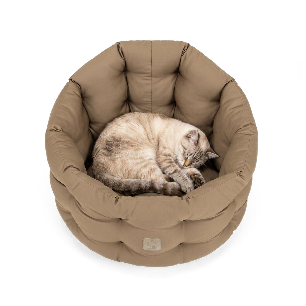 Rundes, braunes Katzenbett Deluxe mit einer schlafenden Katze in der Mitte, weich gepolstert und gemütlich.