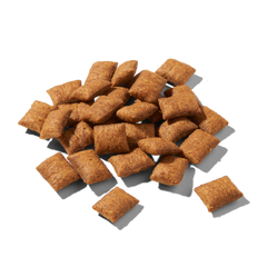 Knusprige, braune Cerealienstücke von FELIA Snacks Huhn auf schwarzem Hintergrund.