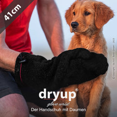 Handwerker mit schwarzem dryup® Handschuh betrachtet kleinen Hund, Länge 41 cm, unscharfer Hintergrund.