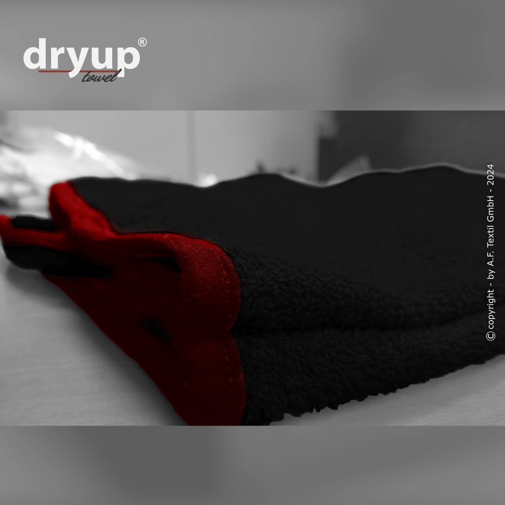 Schwarzes Dryup® Handtuch mit roten Akzenten, flauschige Textur und moderne Schriftart. Ideal für Komfort und Stil.