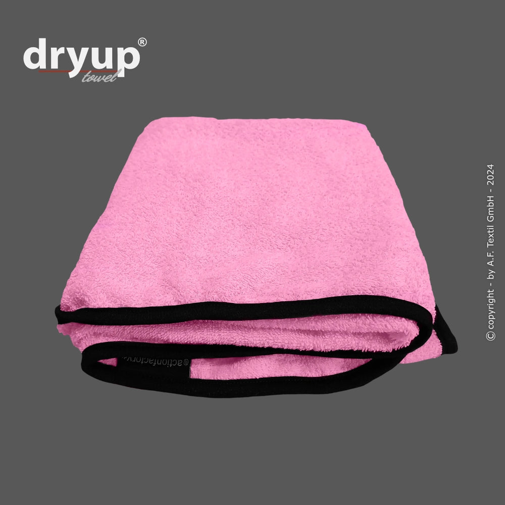 Pink gefaltetes Dryup® Handtuch mit schwarzer Umrandung, weich und bequem, mit Logo in der oberen Ecke.