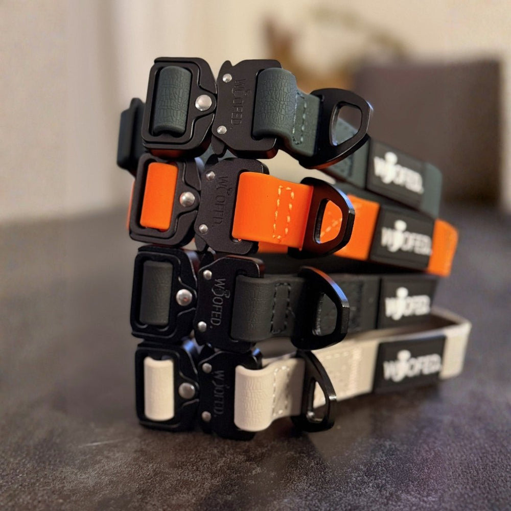 Verschiedene farbige Riemen des WOOFLEX® Tactical Halsbands, verstellbar ohne Griff, in Schwarz, Grün, Orange und Grau.