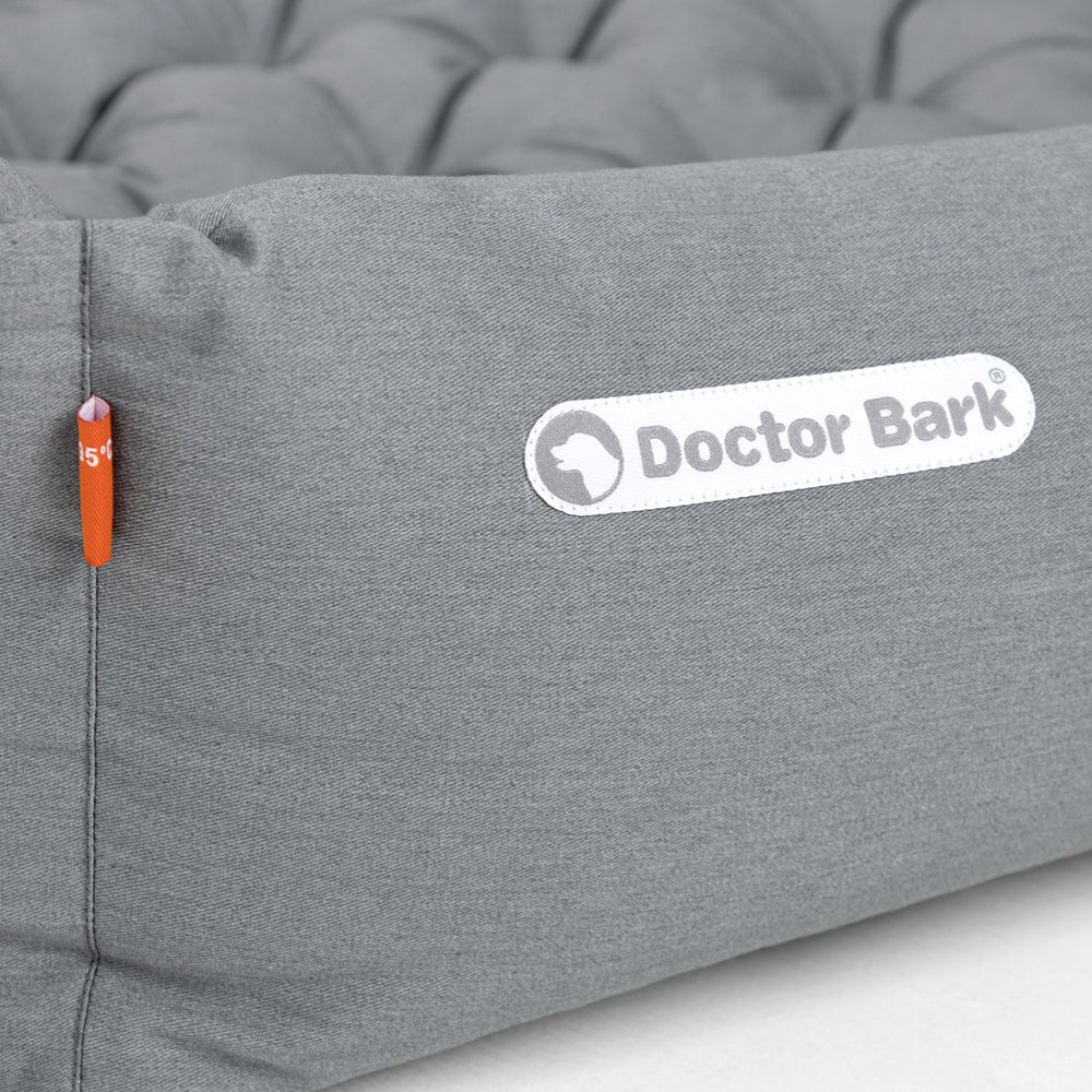 Graues orthopädisches Hundebett von Doctor Bark mit gestepptem Design und orangefarbener Kennzeichnung.