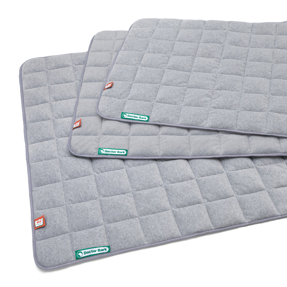 Graue fleece Steppdecke mit kariertem Muster und abgerundeten Ecken, ideal für Komfort und Wärme.